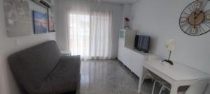 ein Wohnzimmer mit einem Sofa, einem Tisch und einer Uhr in der Unterkunft Acogedor apartamento en Daimús junto a la playa con parking privado y piscinas comunitarias in Daimús