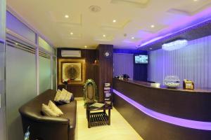 um bar com um sofá de couro num quarto com iluminação roxa em Hotel Blue Bird, Nagaon em Nowgong
