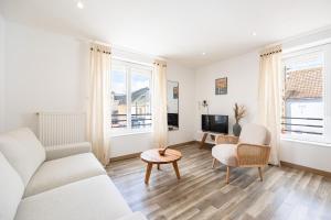 a living room with a couch and chairs and a tv at Duplex Petit-Fort Philippe in Gravelines