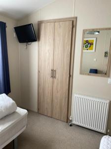 a bedroom with a wooden cabinet and a mirror at Nodes Point Sandy Bay AP27 affordable ferry prices available in Saint Helens