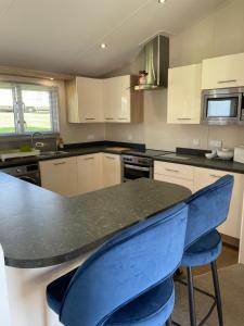 a kitchen with a black counter top and blue chairs at Nodes Point Sandy Bay AP27 affordable ferry prices available in Saint Helens