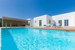 a swimming pool in front of a house at Summera villas Paros in Chrissi Akti