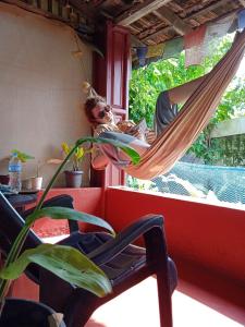 a man is in a hammock in a window at The Blues in Alleppey