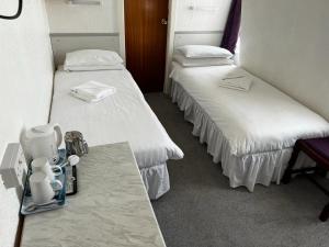 two beds in a hotel room with white sheets at Delton Hotel in Blackpool