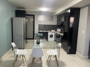 a kitchen with a glass table and white chairs at 104at77 Independence Street - Windhoek in Windhoek