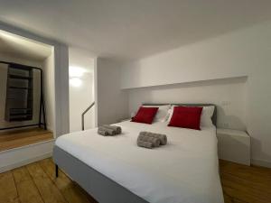 um quarto com uma grande cama branca com almofadas vermelhas em Navigli Design Loft - 7 stops from Duomo, AC, Netflix em Milão