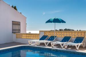 eine Gruppe von Stühlen und einem Sonnenschirm neben einem Pool in der Unterkunft Albufeira Marina Villa in Albufeira
