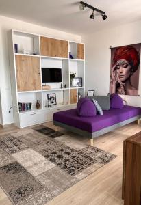 uma sala de estar com um sofá roxo num quarto em Sunset Resort em Vlorë