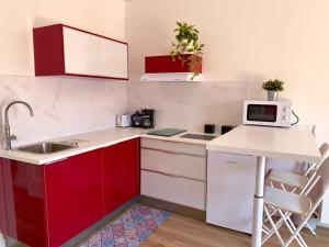 una pequeña cocina con armarios rojos y blancos en Las Vistas-Rincón acogedor con vistas al mar en Tabaiba
