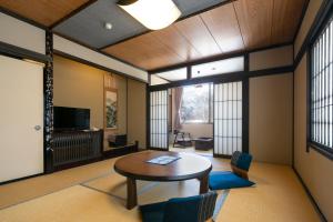 a living room with a table and chairs and a tv at Onyado Hisui in Takayama