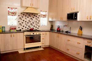 uma cozinha com armários de madeira e um forno com placa de fogão em Cozy Blue Guesthouse em East London