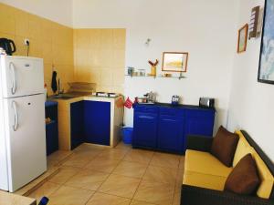 La cuisine est équipée de placards bleus et d'un réfrigérateur blanc. dans l'établissement Casa Branca, à Porto Novo