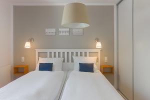 two beds in a bedroom with two blue pillows at Hein Krabbe Heiligenhafen in Heiligenhafen