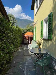 un patio con mesa, sillas y sombrilla en Accogliente appartamento con cucina arredata, en Ascona