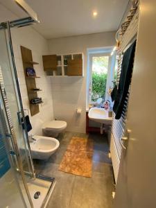 baño con 2 lavabos, aseo y ventana en Accogliente appartamento con cucina arredata en Ascona