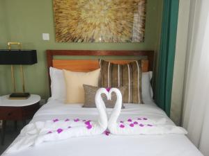 Dos cisnes blancos están sentados en una cama con flores. en Casa nostra, en Kakamega