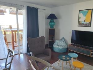 sala de estar con TV y silla en BLUE SUMMER T3 - vue sur mer - Saint Gilles les Bains, en Saint-Gilles-les-Bains