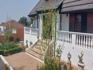 a white house with a white railing and stairs at The Dauphin House in Johannesburg