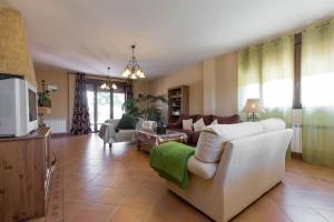 ein Wohnzimmer mit einem weißen Sofa und einem Fernseher in der Unterkunft Los Rosales de Venturada in Venturada