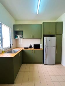 a kitchen with green cabinets and a white refrigerator at LeCOMFY GUESTHOUSE HOMESTAY TAMBUN IPOH with UNIFI, NETFLIX,AIRCOND in Ipoh