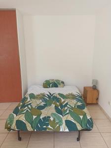 um quarto com uma cama com um cobertor em Spacieux studio tout équipé em Le Tampon