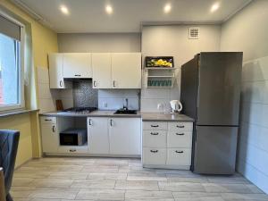  La cuisine est équipée de placards blancs et d'un réfrigérateur. dans l'établissement Apartament COMFORT Centrum, à Krotoszyn