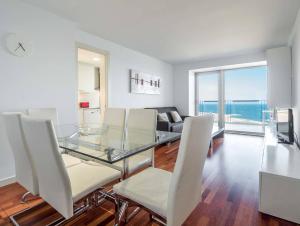 Un comedor con una mesa de cristal y sillas blancas. en Rent Top Apartments Beach-Diagonal Mar, en Barcelona