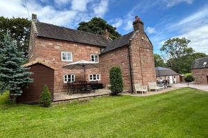een oud bakstenen huis met een paraplu in de tuin bij Character 3 Bed Peak District Farmhouse - Alton Towers, Christmas Markets, Polar Bears, Chatsworth in Cheadle
