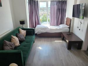 a living room with a green couch and a bed at Cosy 1 Bedroom Flat-Newport (F2) in Newport