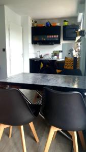 a kitchen with a table and two black chairs at chambre sur Muret in Muret