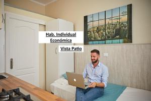 un hombre sentado en una cama con un portátil en El Sueño De Alejandra - Apartments en Las Palmas de Gran Canaria