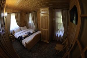 Cette chambre en bois comprend un grand lit. dans l'établissement Cabana Gura Voronețului, à Gura Humorului