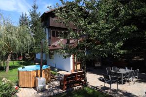 une maison avec une table, des chaises et un arbre dans l'établissement Cabana Gura Voronețului, à Gura Humorului