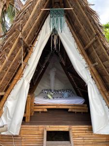ein Bett in der Mitte eines strohgedeckten Zeltes in der Unterkunft Georgia's Neverland Hostel in Malapascua
