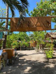 Ein Holzschild, auf dem Garten steht. in der Unterkunft Georgia's Neverland Hostel in Malapascua