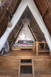 a bed inside of a thatch roofed tent at Georgia's Neverland Hostel in Malapascua Island