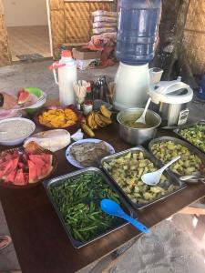 une table recouverte de plateaux de différents types de nourriture dans l'établissement Georgia's Neverland Hostel, à Malapascua