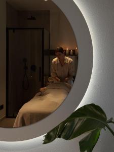 a man sitting on a bed in front of a mirror at Hill Palanga & SPA in Palanga