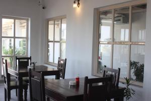 a dining room with a table and chairs and windows at Doongri House in Jaipur