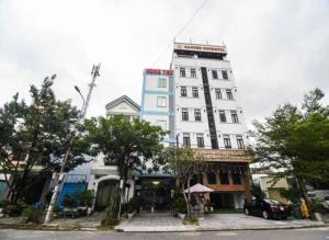 a tall white building sitting on the side of a street at Hùng Thư Motel in Da Nang