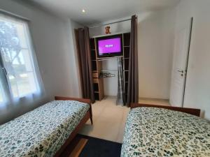 a bedroom with two beds and a tv and a window at Maison pour 4/ 6 personnes les hirondelles in Saint-Vivien-de-Monségur