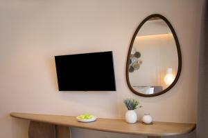 a mirror on a wall next to a table with a tv at Alexandra Golden Boutique Hotel-Adults Only in Chrysi Ammoudia