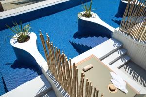 a swimming pool with blue water and bamboo plants at Alexandra Golden Boutique Hotel-Adults Only in Chrysi Ammoudia