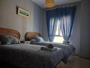 Un dormitorio con dos camas y una ventana con cortinas azules. en AMPLIO PISO EN COSTA BALLENA A 100 M DE LA PLAYA, en Costa Ballena 11 fotos más
