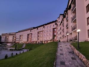 een groot gebouw met een grasveld ervoor bij Kloudscape Apartman Milmari Resort & Spa in Kopaonik