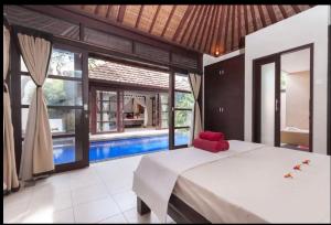 a bedroom with a bed and a swimming pool at Villa Kubu Pratiwi - Villa 2 in Canggu
