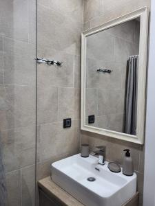 ein Badezimmer mit einem weißen Waschbecken und einem Spiegel in der Unterkunft Kloudscape Apartman Milmari Resort & Spa in Kopaonik