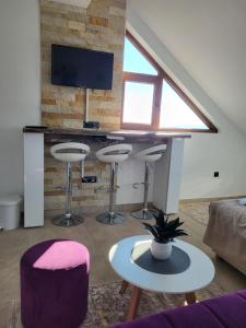 ein Wohnzimmer mit 3 Barhockern und einem TV in der Unterkunft Kloudscape Apartman Milmari Resort & Spa in Kopaonik