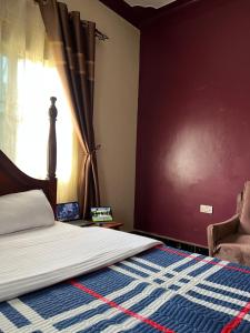 a bedroom with a bed and a window and a chair at Pearl Sanctuary 02_Kisoro Homestay in Kisoro