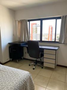 a bedroom with a desk and a chair in front of a window at Loft no Condomínio Celita Franca Executive ApartHotel in Feira de Santana